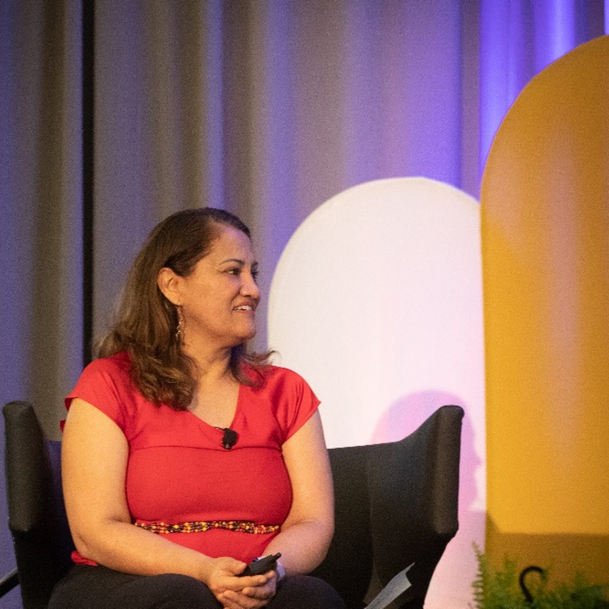 Marta Villanueva seated on a conference panel, listening.