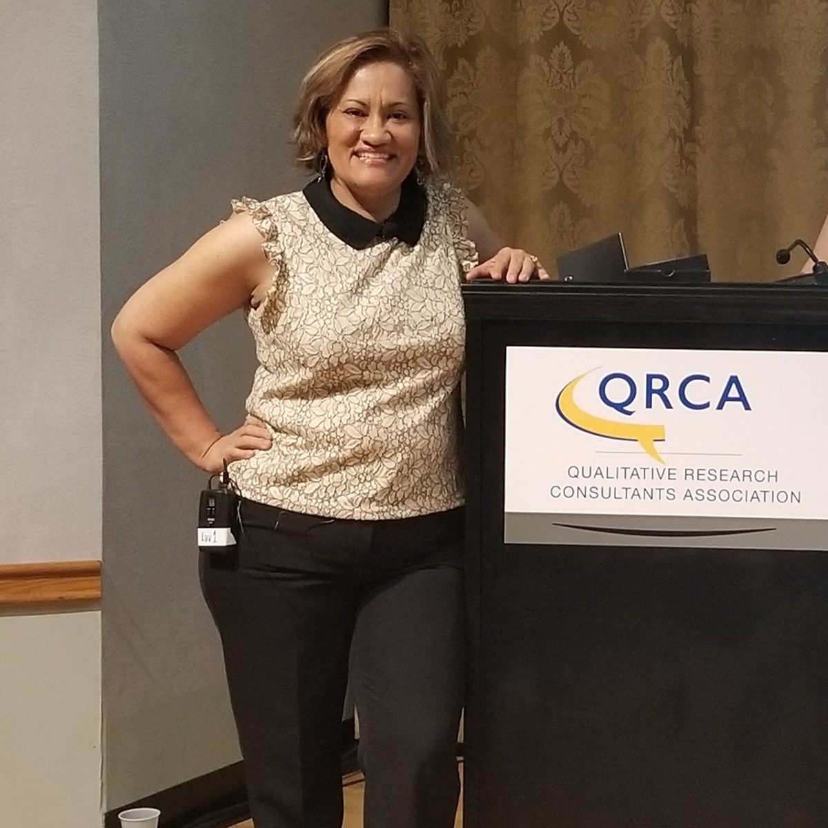 Marta Villanueva beside the podium at a QRCA conference.