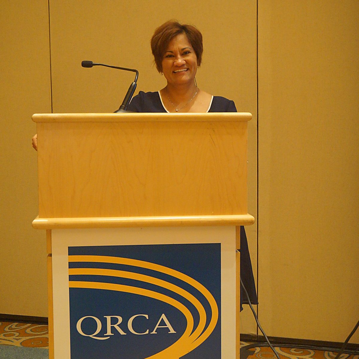 Marta Villanueva presenting from a QRCA podium.