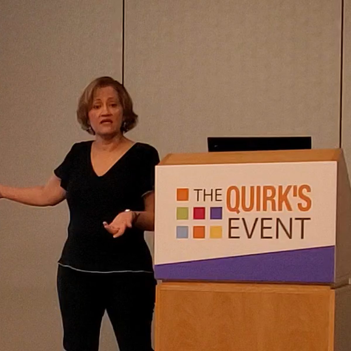 Marta Villanueva presenting beside The Quirk's Event podium.